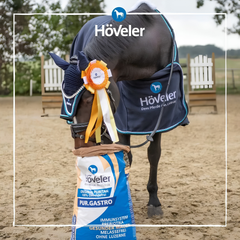 Horse with Höveler blanket beside PUR.GASTRO feed bag, promoting grain-free nutrition for sensitive stomachs.
