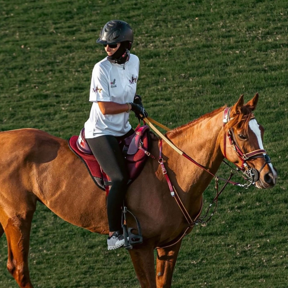 Rider wearing N3F RIDING MASK on a horse in a grassy field, demonstrating premium equestrian gear.