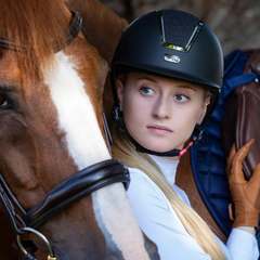 Alzarrab PE Odyssey Horse Riding Helmet-Black worn by a rider next to a horse in Dubai.